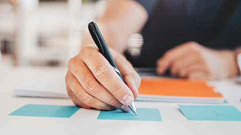 A close view of a programmer writing info on sticky notes