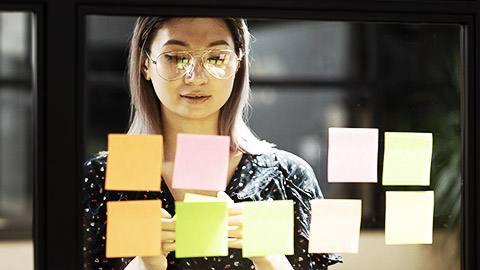 A person looking at stickies ona glass board