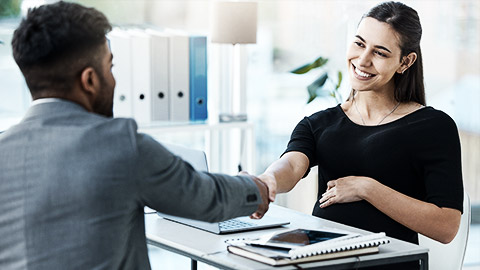 A person shaking hands with a person accross the table