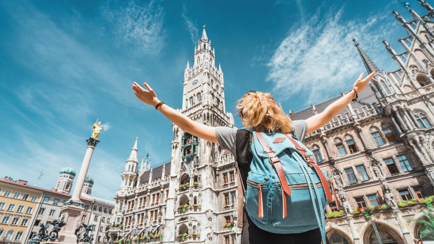 A girl tourist traveler enjoys a Grand view of the Gothic building of the Old town Hall in Munich.