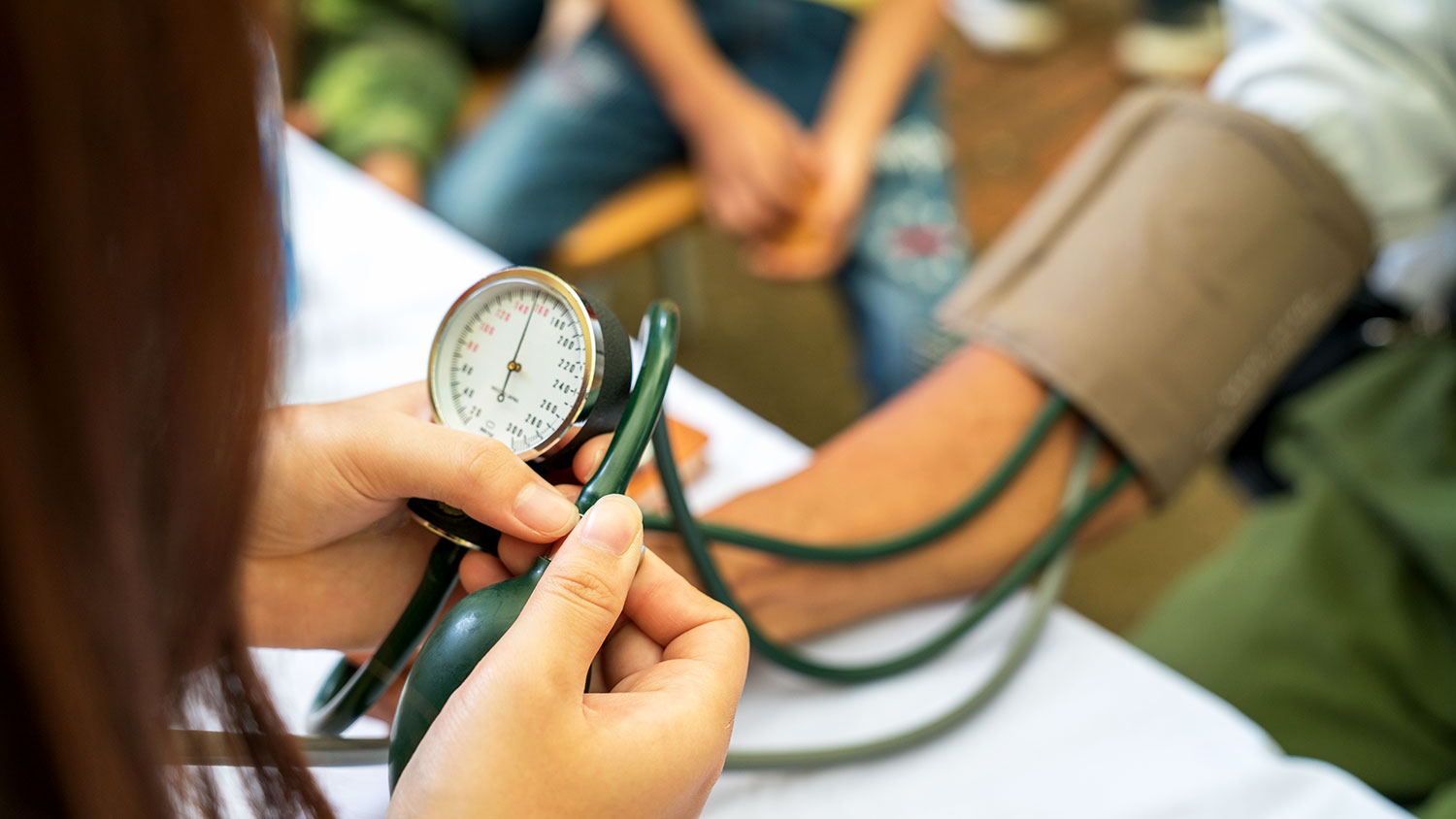 Volunteer nurse measuring blood pressure of poor Asian people outdoors closeup