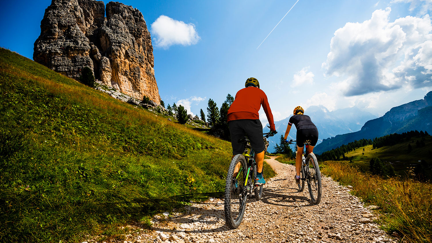 Cycling woman and man riding on bikes in Dolomites mountains landscape. Couple cycling MTB enduro trail track. Outdoor sport activity.