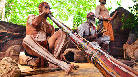 Aboriginal men in traditional outfits playing digeridoos