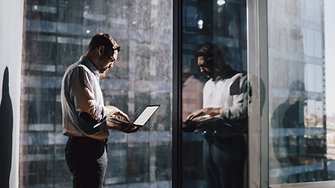 Man standing at window with laptop