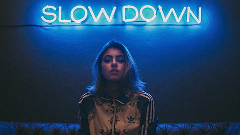 Female on couch underneath neon sign