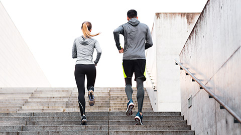 Male and female runners climbing stairs