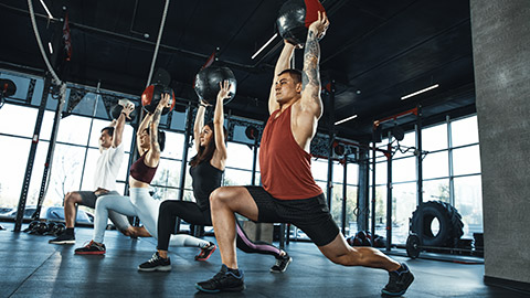 Group of fit people working out with medicine balls in gym