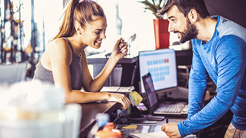 Male trainer talking to female client at reception of gym