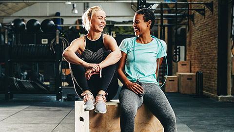 Two women sitting on an exercise box after a workout