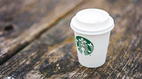 Starbucks cup with shallow depth of field image sitting on a rustic wooden table