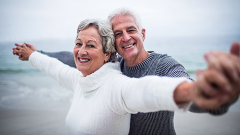 Senior couple smiling at the beach