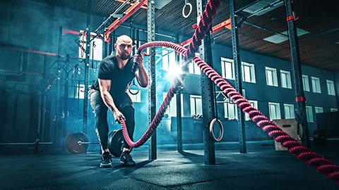 man using battle rope in gym