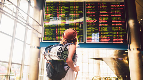 young female traveller looking at airport departure board