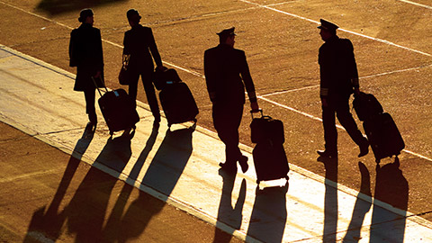 flight crew walking across tarmac at sunset