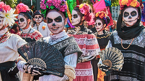 people wearing masks in a day of the dead parade