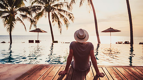 man relaxing next to pool