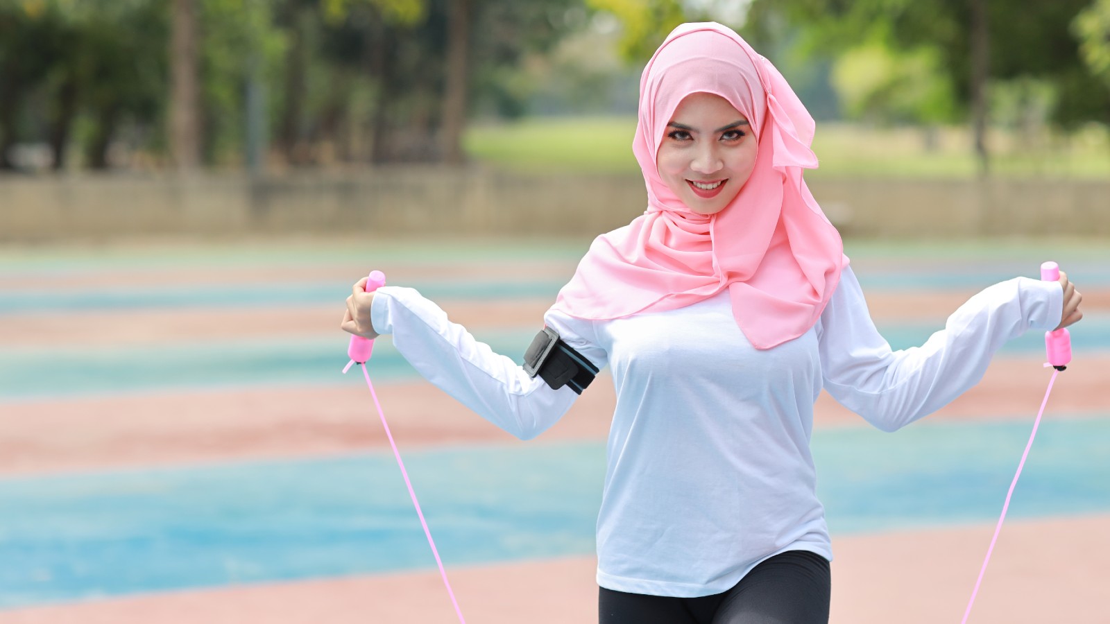 Young woman, wearing fitness attire and a hijab, holding a skipping rope