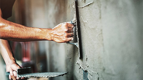 A worker plastering cement on the wall while building a house