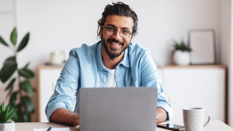 Smiling designer sitting at desk with laptop