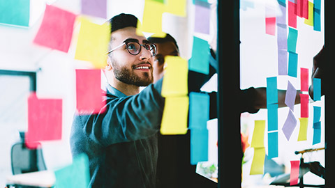 Male graphic designer working on wall with post-it notes