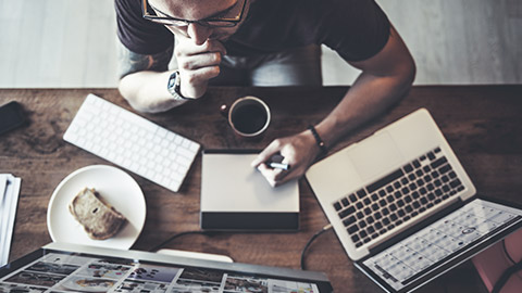 Top down shot of designer working on laptop and desktop computer