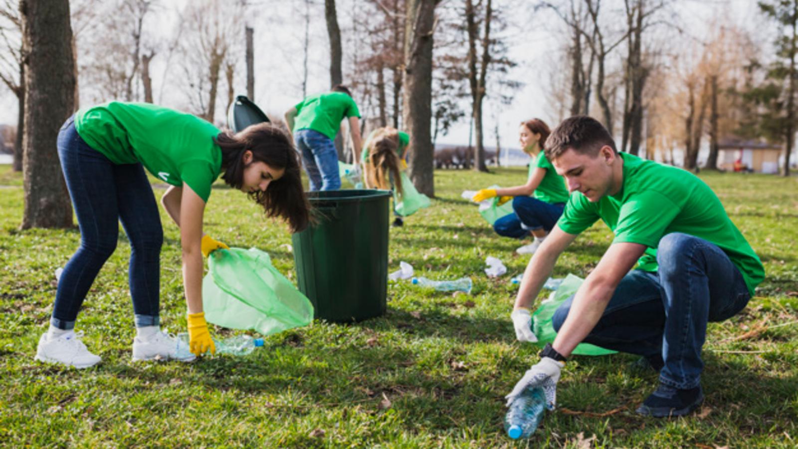 group of young volunteers collecting garbage off lawn