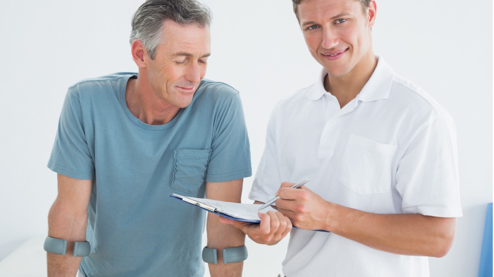 Man on crutches discussing exercise plan with fitness instructor