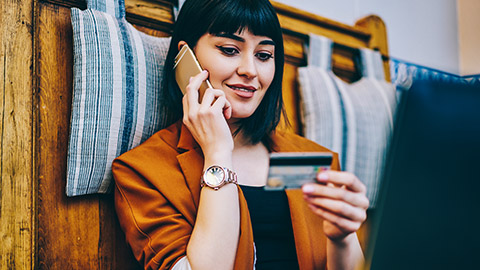 Woman holiding credit card while talking on mobile phone