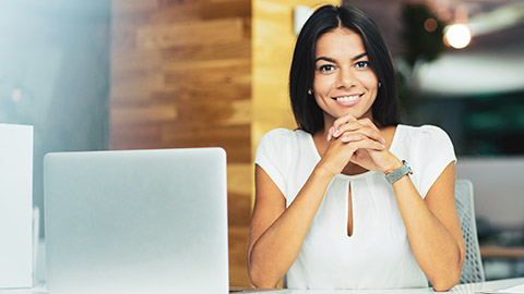 Female business person sitting at desk in office looking to camera