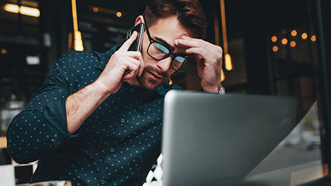 Male business man talking on phone with laptop in front of him