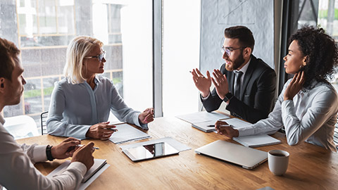 Business eople sitting at a table discussing business with serious looks on their faces