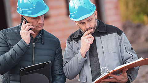 2 managers on building site consulting notes on legislation