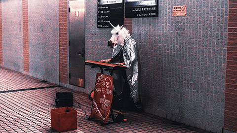 Busker wearing horse head mask playing instrument